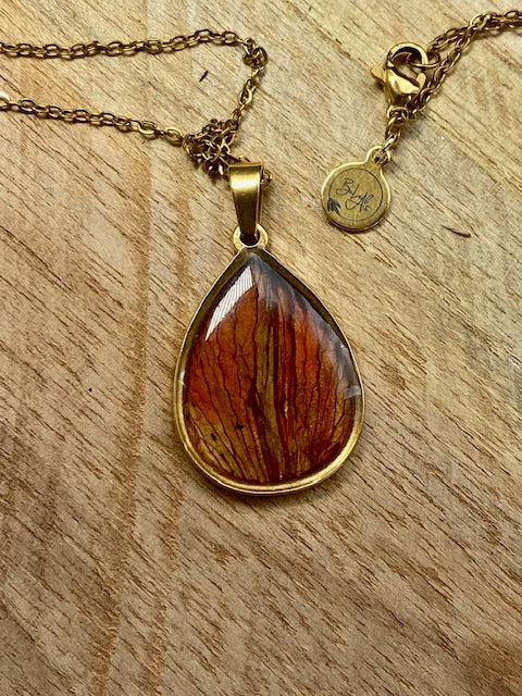 Beautiful gold-colored drop pendant with dried red lily leaves.
