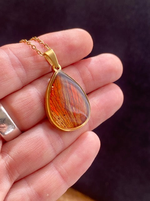 Beautiful gold-colored drop pendant with dried red lily leaves.
